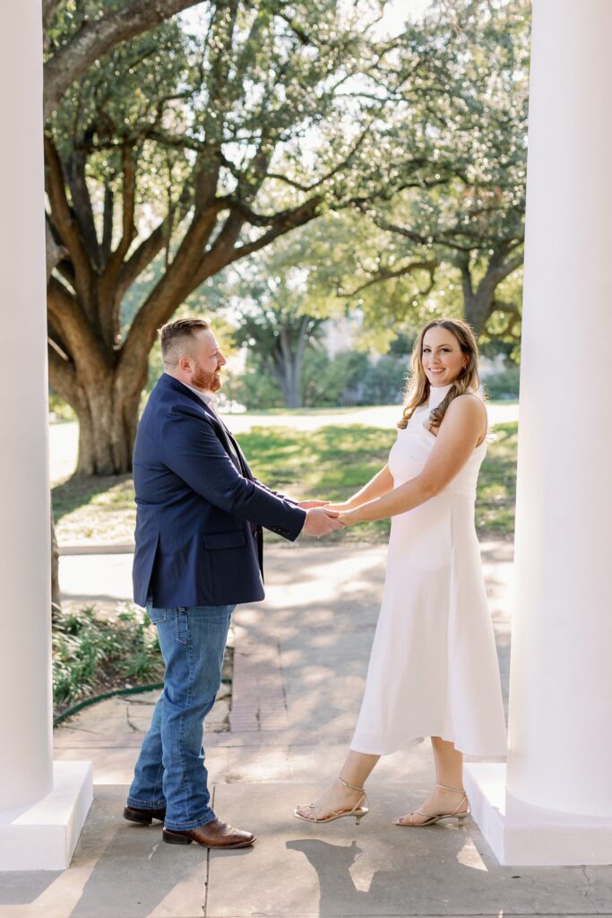 Engagement portrait of Madeline in a white dress standing with Ryan by the steps